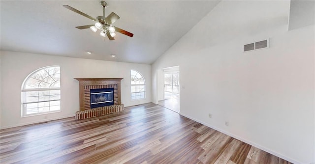 unfurnished living room with wood-type flooring, a wealth of natural light, a fireplace, and ceiling fan