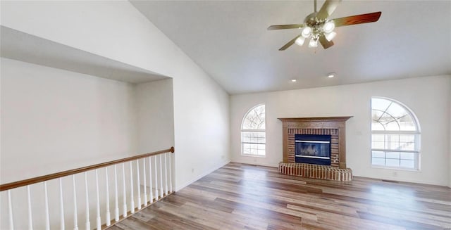 unfurnished living room with ceiling fan, lofted ceiling, a fireplace, and light hardwood / wood-style floors