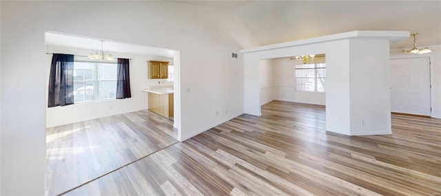 interior space with a notable chandelier, vaulted ceiling, and light hardwood / wood-style floors