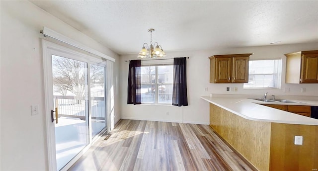 kitchen with sink, decorative light fixtures, a chandelier, a textured ceiling, and kitchen peninsula