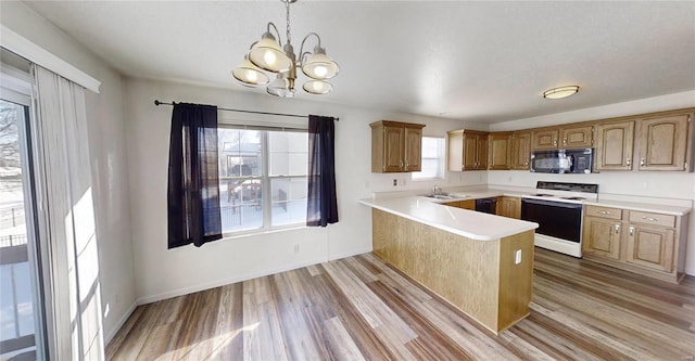 kitchen with a chandelier, light hardwood / wood-style flooring, kitchen peninsula, pendant lighting, and black appliances