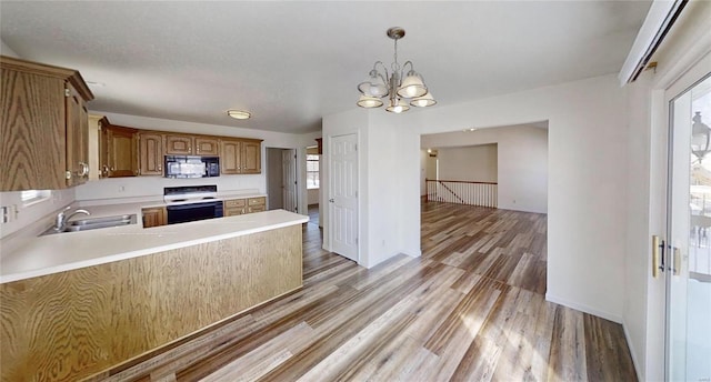 kitchen featuring sink, electric range oven, decorative light fixtures, kitchen peninsula, and a chandelier