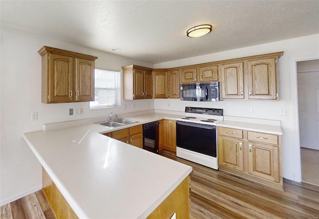 kitchen with black appliances, wood-type flooring, sink, kitchen peninsula, and a textured ceiling