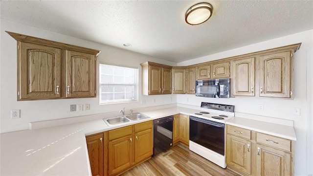 kitchen with sink, light hardwood / wood-style flooring, black appliances, and a textured ceiling