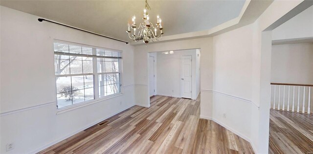 unfurnished dining area with an inviting chandelier and light hardwood / wood-style floors