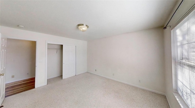 unfurnished bedroom with light colored carpet and a closet