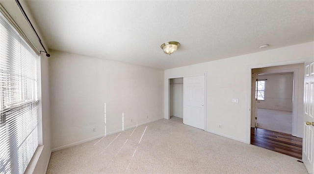 unfurnished bedroom with light carpet and a closet