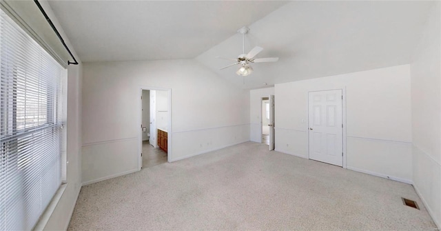 empty room featuring ceiling fan, vaulted ceiling, and light carpet