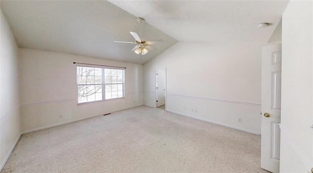 empty room featuring ceiling fan, vaulted ceiling, and light carpet