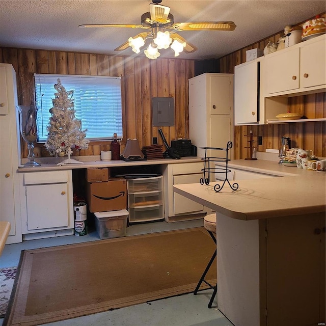 kitchen with white cabinets, kitchen peninsula, a breakfast bar area, and a textured ceiling