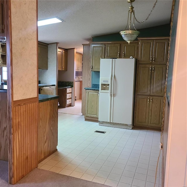 kitchen featuring a textured ceiling, vaulted ceiling, wooden walls, white refrigerator with ice dispenser, and light tile patterned floors