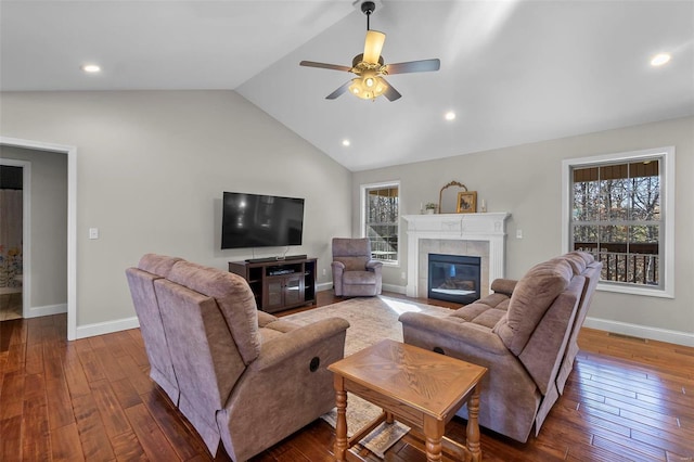 living room featuring a tile fireplace, dark hardwood / wood-style floors, high vaulted ceiling, and ceiling fan