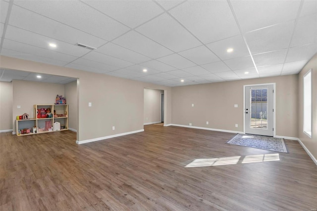 interior space with a paneled ceiling and dark hardwood / wood-style floors