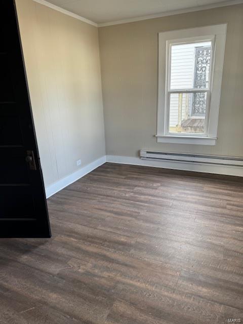 spare room with ornamental molding, dark wood-type flooring, and a baseboard heating unit