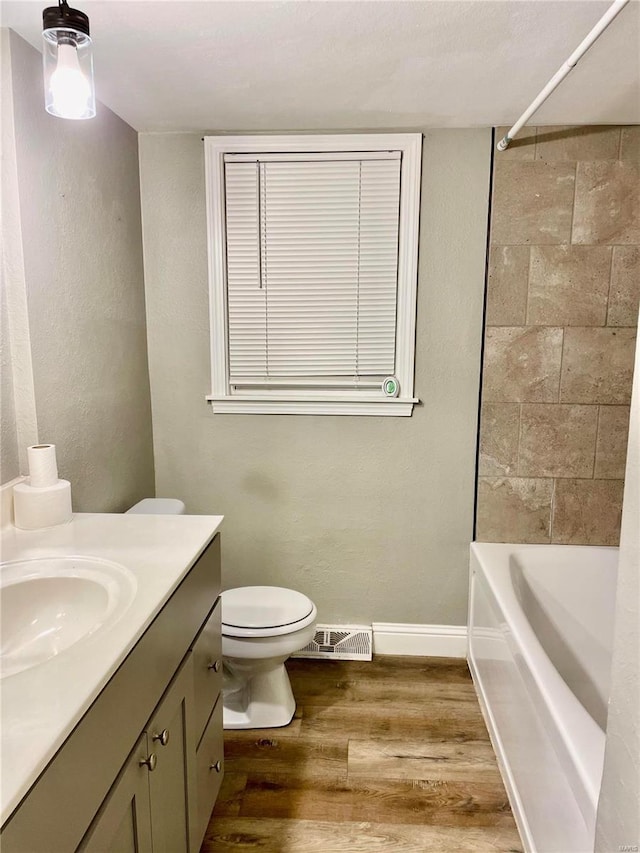 full bathroom featuring hardwood / wood-style flooring, vanity, toilet, and tiled shower / bath combo