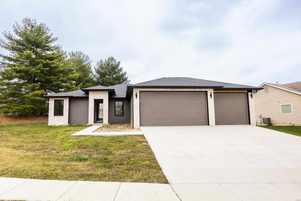 prairie-style home with a front yard, central AC unit, and a garage