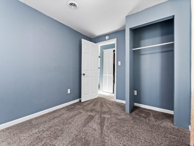 unfurnished bedroom featuring a closet and dark carpet