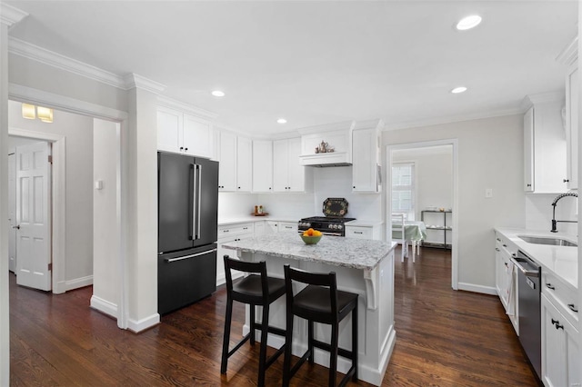 kitchen with sink, appliances with stainless steel finishes, a center island, light stone counters, and white cabinets