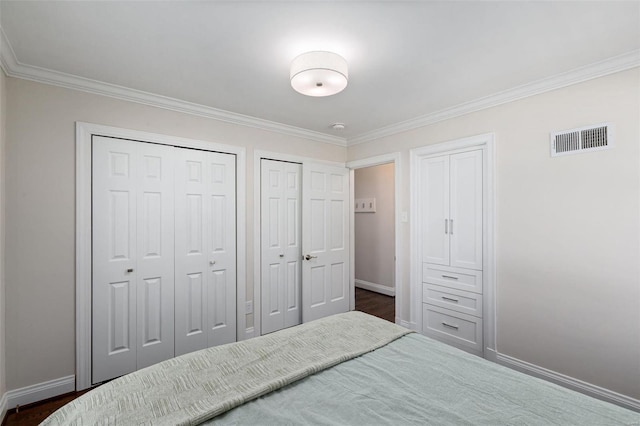 bedroom featuring multiple closets, crown molding, and dark wood-type flooring