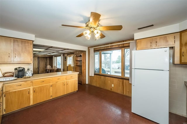 kitchen featuring white refrigerator, ceiling fan, and wood walls