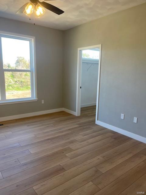 spare room featuring a healthy amount of sunlight, ceiling fan, and light hardwood / wood-style floors