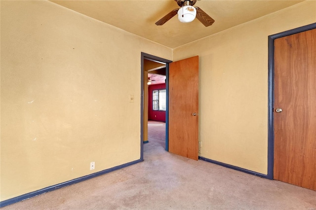 empty room featuring ceiling fan and light carpet