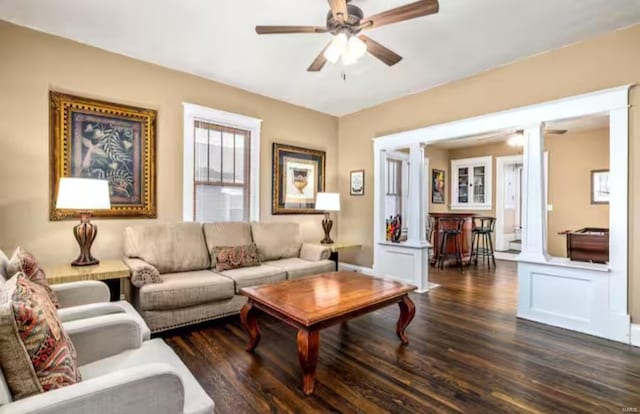 living room with ornate columns, ceiling fan, and dark wood-type flooring