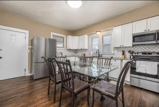 kitchen with backsplash, white cabinetry, stainless steel appliances, and dark hardwood / wood-style floors