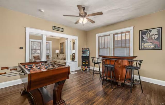 recreation room with bar area, ceiling fan, and dark hardwood / wood-style flooring