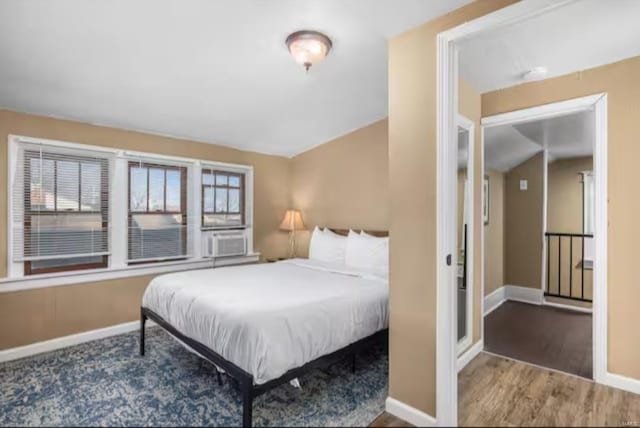 bedroom featuring cooling unit, vaulted ceiling, dark wood-type flooring, and multiple windows