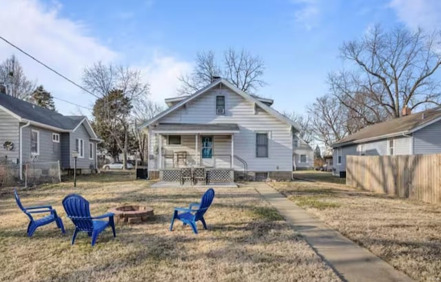 back of property featuring a lawn, a porch, and an outdoor fire pit