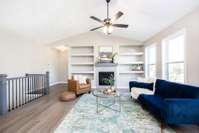 living room featuring built in shelves, ceiling fan, vaulted ceiling, and hardwood / wood-style flooring