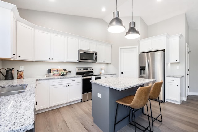 kitchen featuring white cabinets, stainless steel appliances, lofted ceiling, and a kitchen island