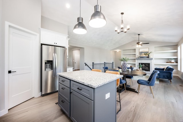 kitchen with a kitchen island, stainless steel refrigerator with ice dispenser, decorative light fixtures, white cabinets, and light wood-type flooring