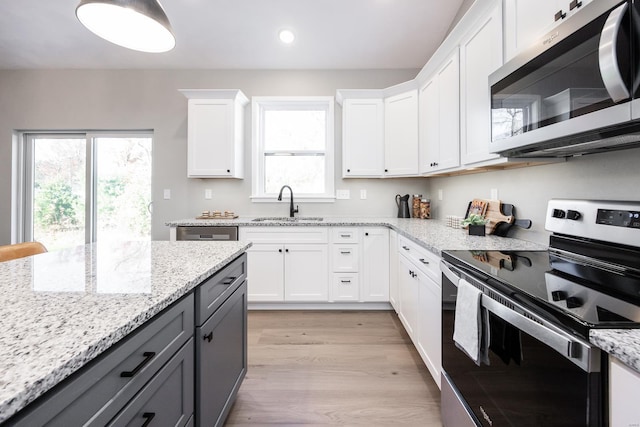 kitchen featuring gray cabinetry, white cabinets, sink, light hardwood / wood-style flooring, and appliances with stainless steel finishes