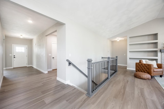 interior space with built in features, wood-type flooring, and lofted ceiling