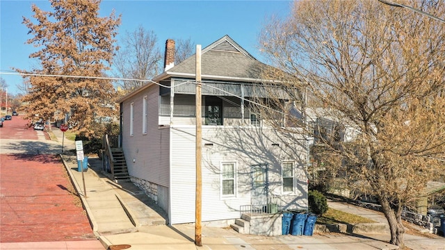 view of side of home with a shingled roof and a chimney