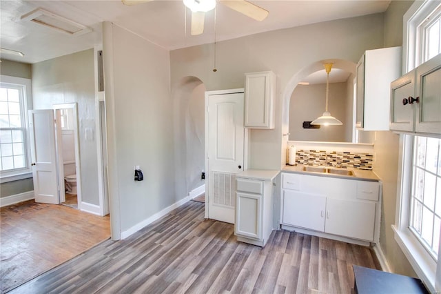 kitchen featuring light wood finished floors, light countertops, hanging light fixtures, decorative backsplash, and white cabinets