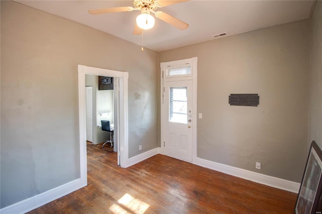 foyer with dark wood-type flooring, visible vents, ceiling fan, and baseboards