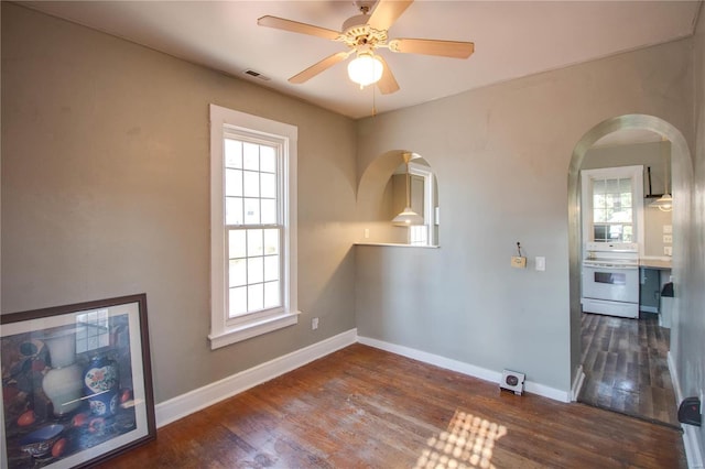 empty room with a ceiling fan, dark wood-style flooring, visible vents, and baseboards