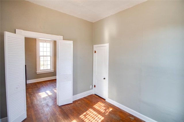 spare room featuring dark wood-style floors and baseboards