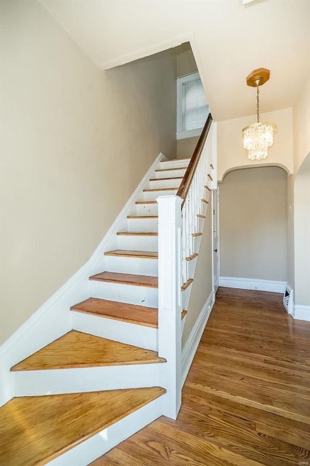 stairway featuring hardwood / wood-style floors and a chandelier