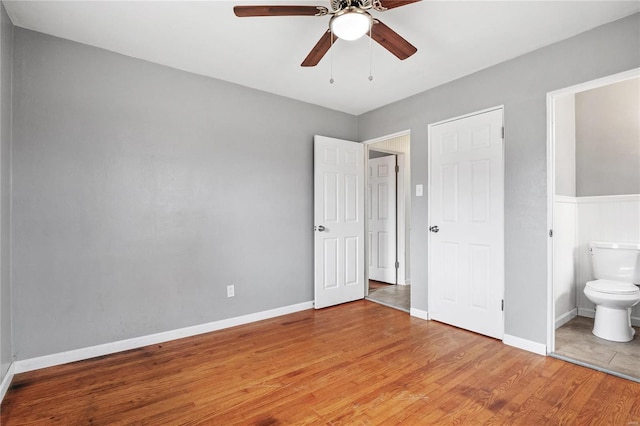 unfurnished bedroom with light wood-type flooring, connected bathroom, and ceiling fan