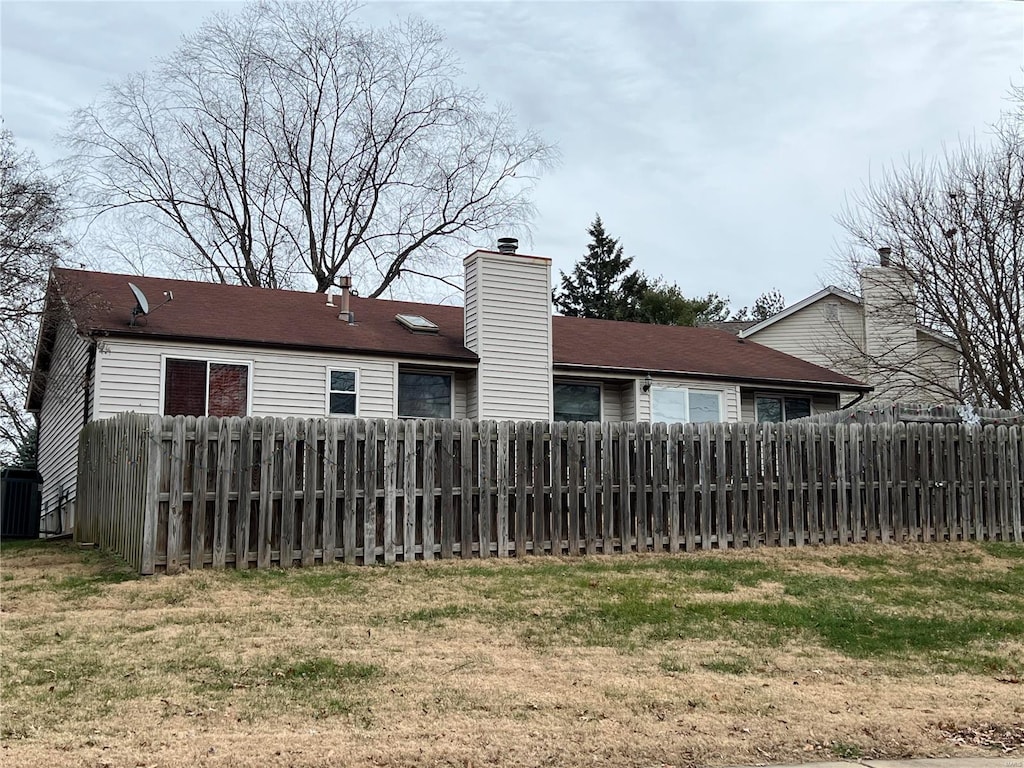 back of property with a chimney and fence