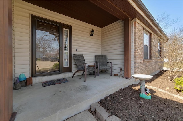 property entrance with brick siding and a porch