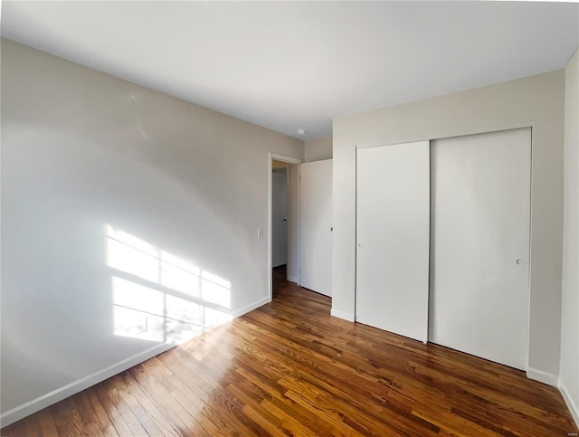 unfurnished bedroom featuring dark hardwood / wood-style flooring and a closet