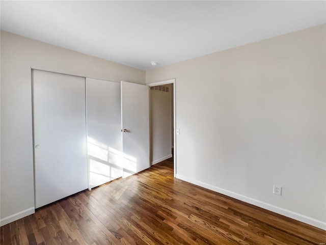 unfurnished bedroom with dark hardwood / wood-style flooring and a closet