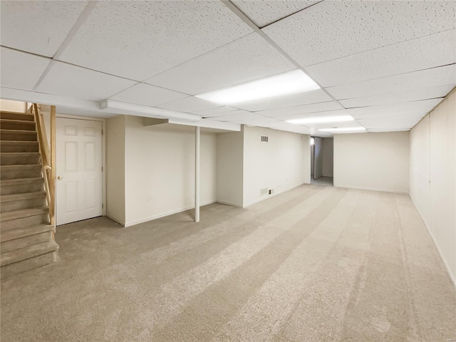 basement featuring a paneled ceiling and carpet