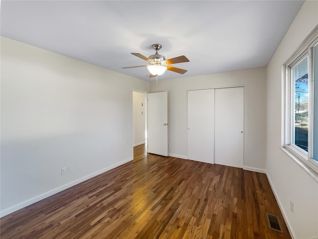 unfurnished bedroom featuring a closet, dark hardwood / wood-style floors, and ceiling fan