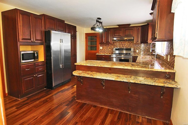 kitchen featuring sink, hanging light fixtures, dark hardwood / wood-style flooring, kitchen peninsula, and appliances with stainless steel finishes